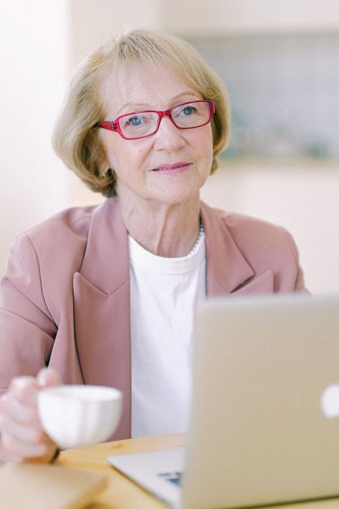A smiling woman with a cup of coffee using her laptop