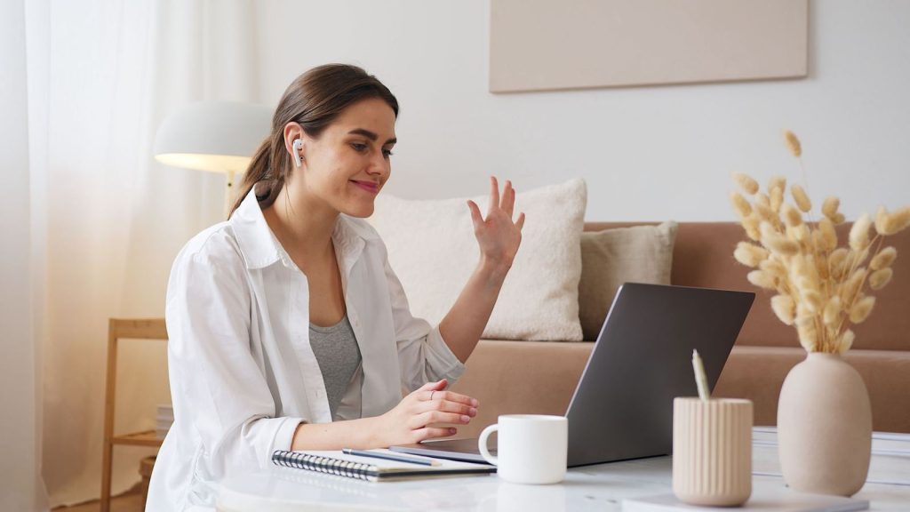 A woman waving hello on a video call